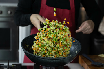 Chef cook roasts vegetables in wok pan on gas stove. Flying vegetable food levitation in motion,...
