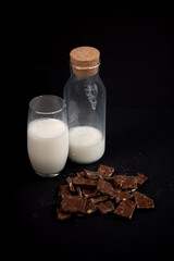 pieces of chocolate and a bottle of milk on a black background