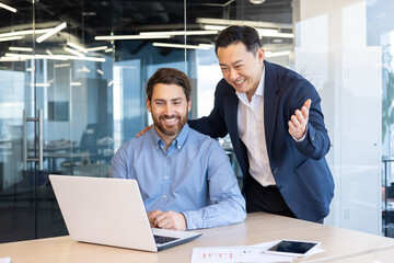 Asian senior boss helping colleague on new employee at workplace inside office, man supports...