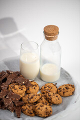milk bottle with glass of milk and cookies on white background
