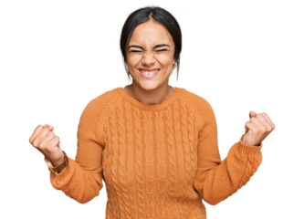 Young brunette woman wearing casual winter sweater very happy and excited doing winner gesture with arms raised, smiling and screaming for success. celebration concept.