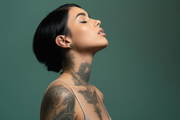 A woman with a tattoo on her neck has her eyes closed - obrazy, fototapety, plakaty