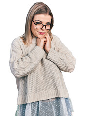 Young blonde woman wearing glasses laughing nervous and excited with hands on chin looking to the side