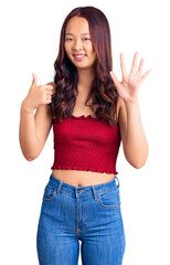 Young beautiful chinese girl wearing casual clothes showing and pointing up with fingers number six while smiling confident and happy.