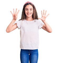 Cute hispanic child girl wearing casual white tshirt showing and pointing up with fingers number nine while smiling confident and happy.