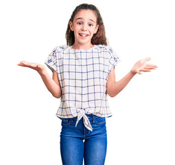 Cute hispanic child girl wearing casual clothes clueless and confused expression with arms and...