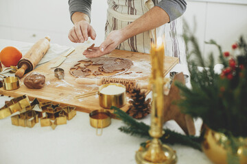 Man making christmas gingerbread cookies close up in modern white kitchen. Hands cutting...