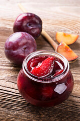 Ripe plums from organic cultivation and marmalade offered as close-up on a rustic wooden design board