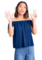 Young beautiful chinese girl wearing casual clothes showing and pointing up with fingers number eight while smiling confident and happy.