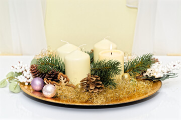 Advent wreath with burning candle against yellow wall - 687698772