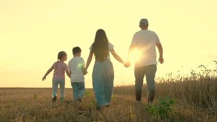 Son daughter dad mom walk hand in hand in child. Happy family of farmers with children walks through wheat field, sunset. Big family, group of people in nature. Childrens dream, complete family, kids