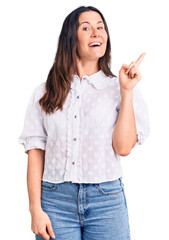 Young beautiful brunette woman wearing casual shirt with a big smile on face, pointing with hand and finger to the side looking at the camera.