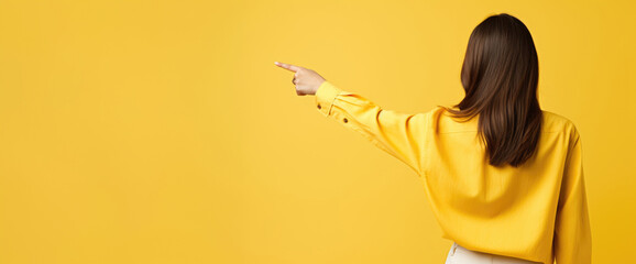 A woman's hand elegantly guides attention to an empty space against a warm yellow background, creating an inviting spot for your text