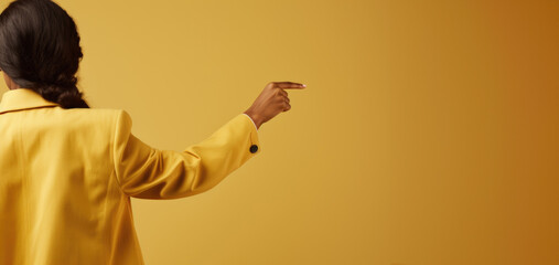 A woman's hand gracefully gestures towards an empty spot on a vibrant yellow background, setting the stage for your text or creative touch