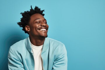 Joyful African-American man beaming with happiness on a vibrant turquoise backdrop, spreading positive vibes