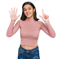 Young hispanic girl wearing casual clothes showing and pointing up with fingers number seven while smiling confident and happy.