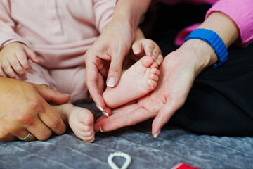 Small children's feet in their parents' hands.