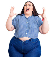 Young plus size woman wearing casual clothes crazy and mad shouting and yelling with aggressive...