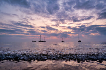 A group of sailboats rests during sunrise on the coast of Peñiscola.