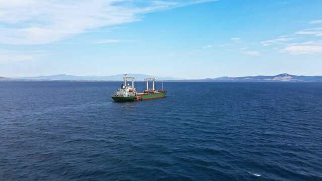 Aerial shot of bulk carrier ship anchored with pilot boat for delivery provisions and crew change