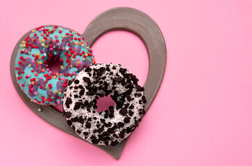 two donuts in a heart-shaped frame on a pink background