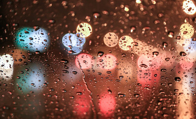 View of the night street through a wet windshield.