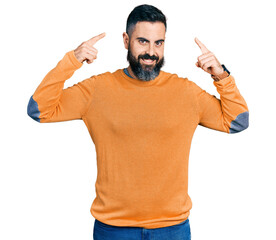 Hispanic man with beard wearing casual winter sweater smiling pointing to head with both hands finger, great idea or thought, good memory