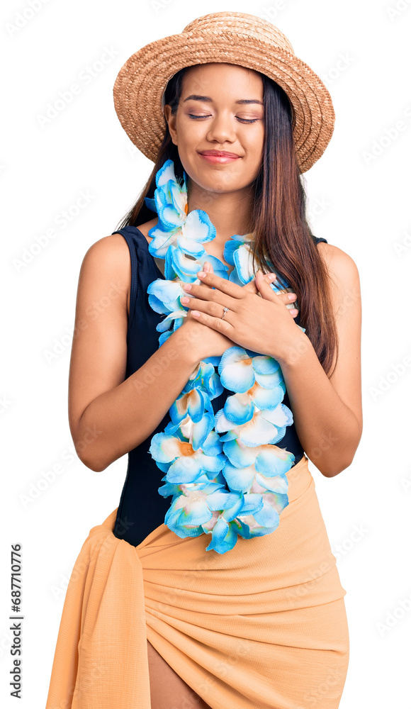 Sticker young beautiful latin girl wearing hawaiian lei and summer hat smiling with hands on chest with clos