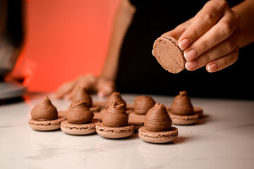 Woman's hand holds one half of a macaroon over the other halves smeared with cream