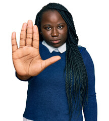 Young black woman with braids wearing casual clothes doing stop sing with palm of the hand. warning...