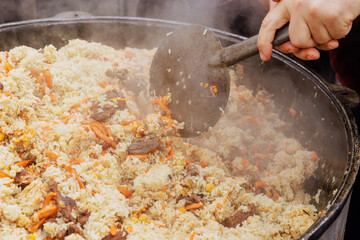 Street food festival cooks traditional Uzbek pilaf in cauldron