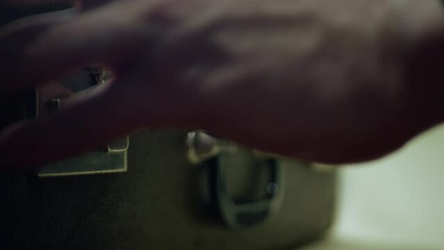 The moment of opening a vintage suitcase with two outlandish locks. Static shooting with focus on the fingers of a man opening a suitcase.