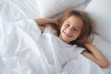 Obraz na płótnie Canvas Top view Portrait of Cute happy smiling kid in bed in the morning on clean white linens. A healthy sleep routine. 