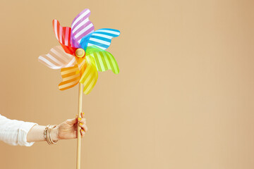 Stylish woman in blouse and shorts with windmill toy on beige