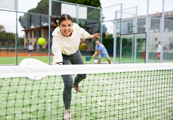 Sportive young girl with racquet playing padel in court