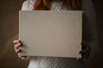 Female hands holding square photo book for wedding album. Wedding photo book, family album. Photo...