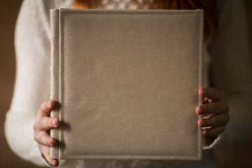 Female hands holding square photo book for wedding album. Wedding photo book, family album. Photo...