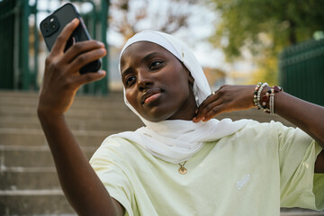 Young muslim woman looking at the mobile on the street