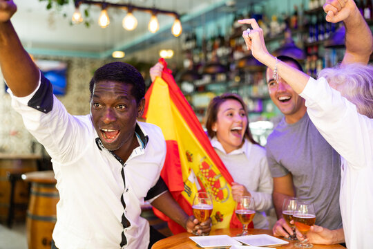 Joyful fans of the Spain team celebrating the victory in the night bar