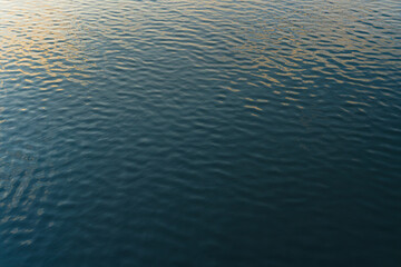 close up lake water background reflect the sunset sky, Golden and blue water ripples texture
