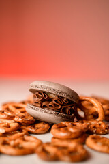 Chocolate macaroon with cream lies among pretzels