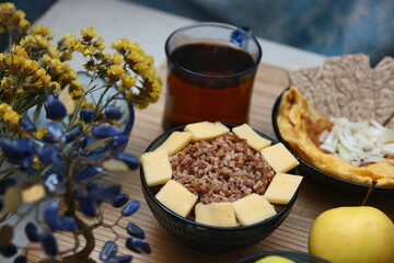 Homemade Ukrainian dinner - buckwheat with cheese, apples, tea. In blue and yellow colors.
