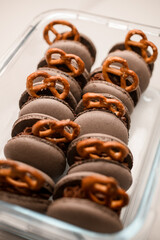Set of gray macaroons decorated with pretzels lie in a container