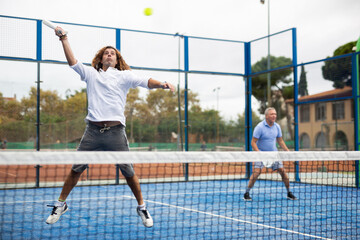 Caucasian man playing paddle tennis on the padel court