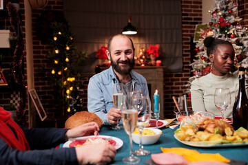Young man enjoying festive xmas dinner with diverse people, meeting with family around the table...