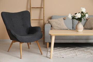 Armchair with couch, ladder and coffee table near beige wall