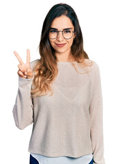 Beautiful hispanic woman wearing casual sweater and glasses showing and pointing up with fingers number two while smiling confident and happy.