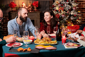 Festive persons celebrating christmas event at table, gthering at home to enjoy traditional food. Diverse friends and family members having fun talking about memories, xmas celebration party.