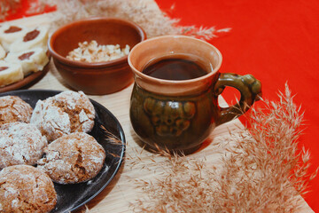 Homemade baked goods - handmade grilled cookies, chopped dumplings, nuts, clay cup of tea on a red background.