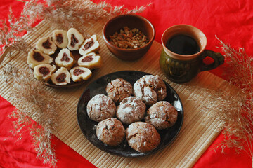 Homemade baked goods - handmade grilled cookies, chopped dumplings, nuts, clay cup of tea on a red background.